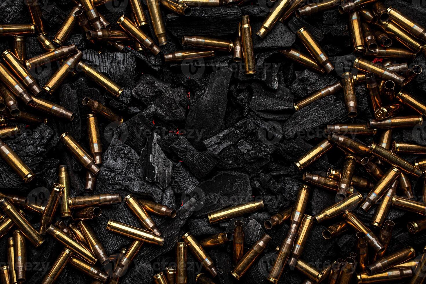Empty shells from weapons on black smoldering coals. Consequences of the war. Dark back. photo