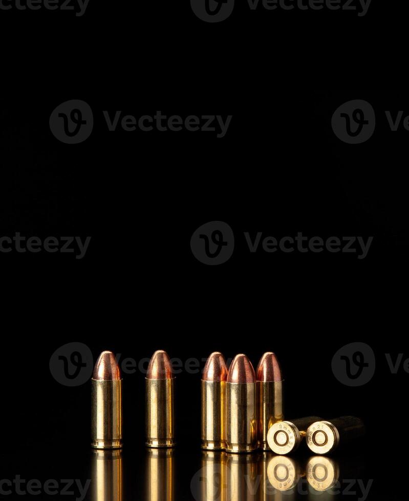 Pistol cartridges 9 mm on a smooth glossy surface with reflections. Ammunition for pistols and PCC carbines on a dark back. photo