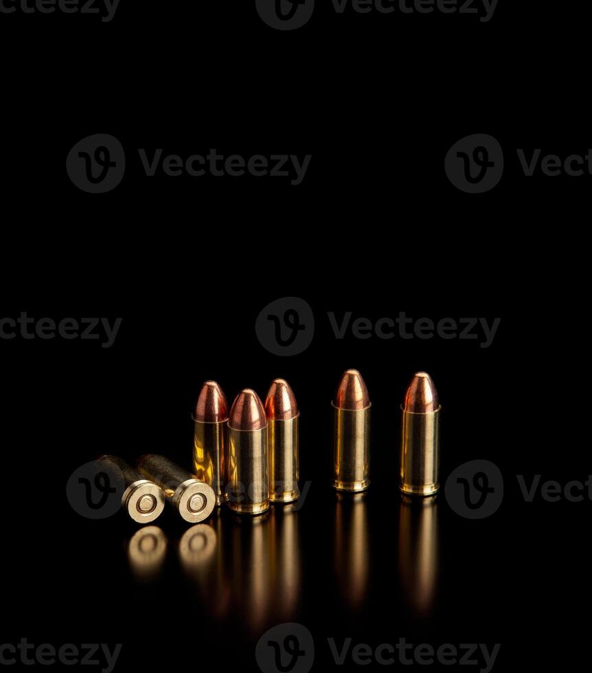 Pistol cartridges 9 mm on a smooth glossy surface with reflections. Ammunition for pistols and PCC carbines on a dark back. photo