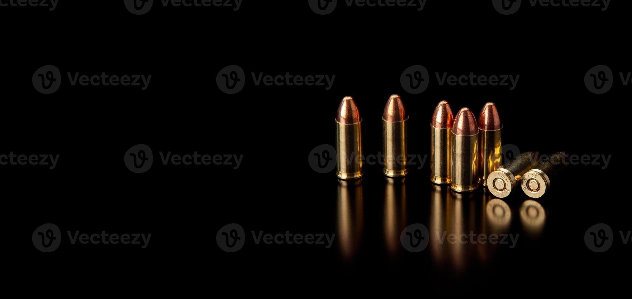 Pistol cartridges 9 mm on a smooth glossy surface with reflections. Ammunition for pistols and PCC carbines on a dark back. photo