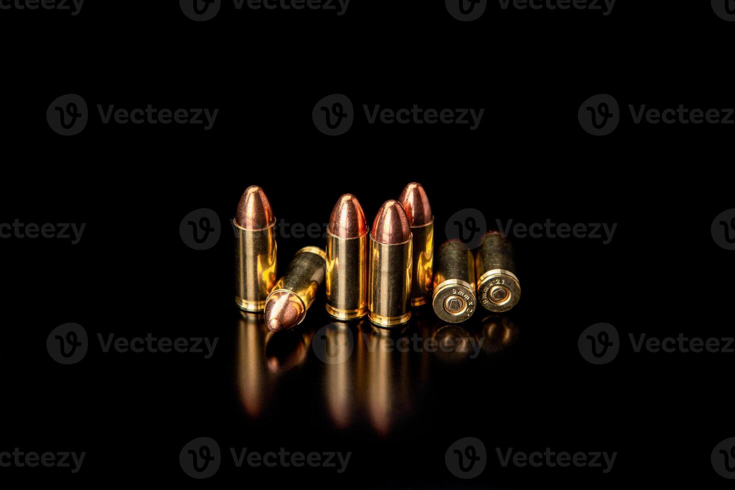 Pistol cartridges 9 mm on a smooth glossy surface with reflections. Ammunition for pistols and PCC carbines on a dark back. photo
