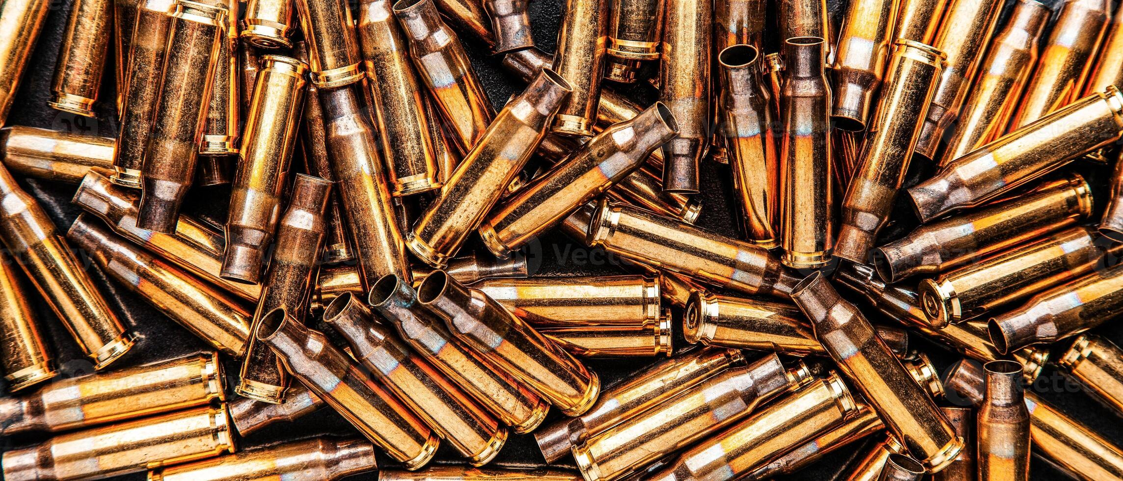 Empty cartridge cases for a carbine or rifle. Background of shiny brass cartridges for cartridges to illustrate armed conflict, war or shooting events. photo