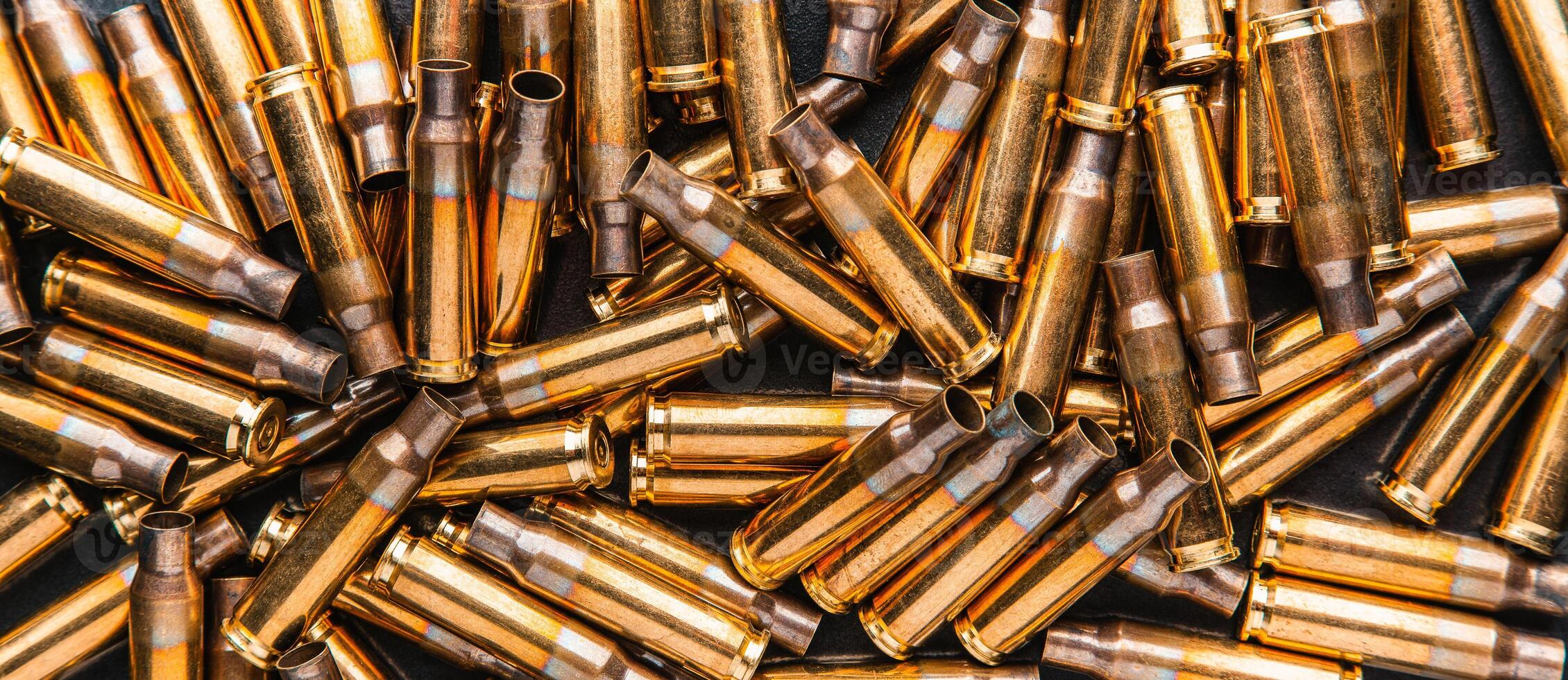 Empty cartridge cases for a carbine or rifle. Background of shiny brass cartridges for cartridges to illustrate armed conflict, war or shooting events. photo