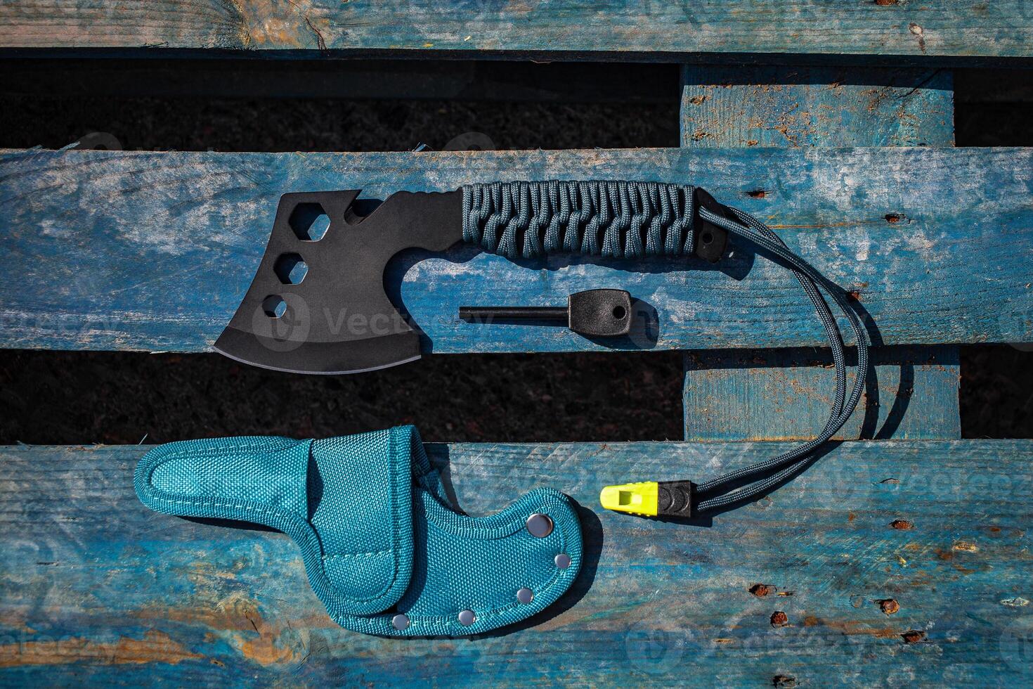 A small black ax with a paracord-wrapped handle. A tool for cutting branches or firewood in the forest. Self defense weapon. Wooden back. photo