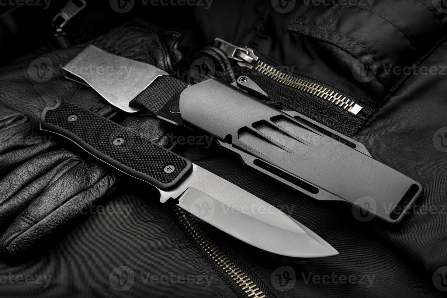 A modern hunting knife with a rubberized handle and a plastic sheath on a dark background. Melee weapons for self-defense and survival. photo