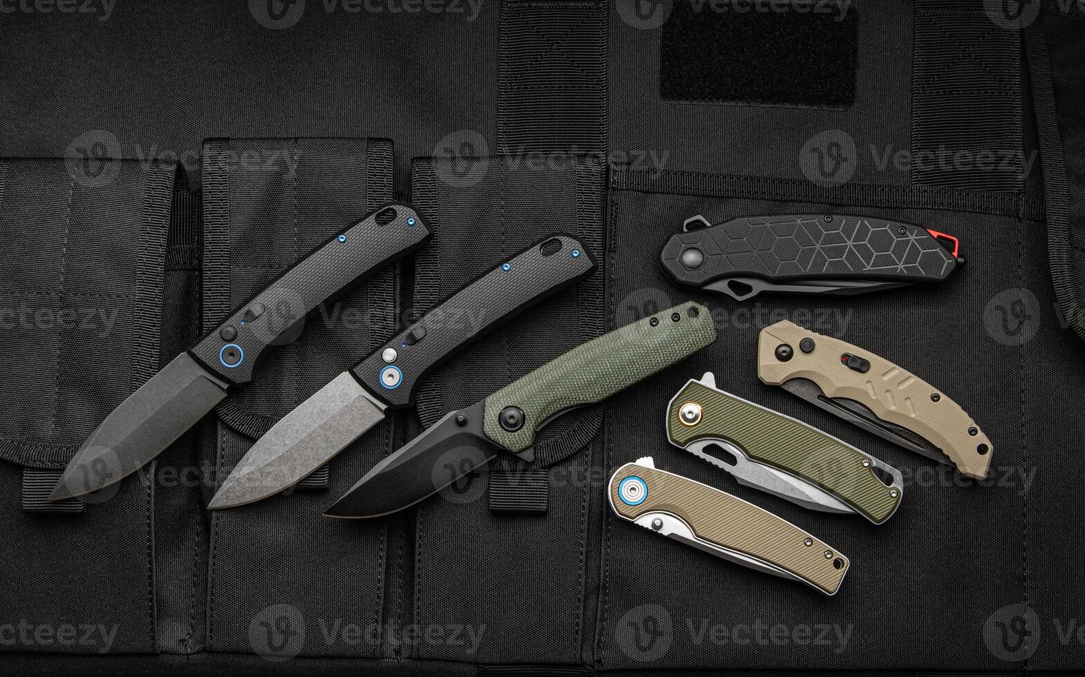 Modern universal pocket folding knives. Penknives lie on a canvas cover with pockets. Dark back. photo