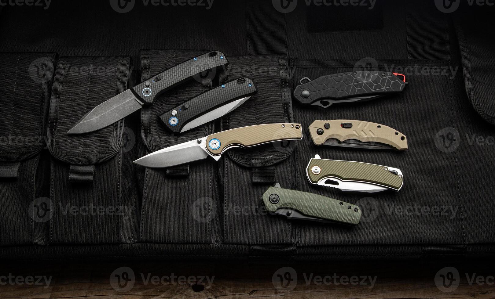 Modern universal pocket folding knives. Penknives lie on a canvas cover with pockets. Dark back. photo