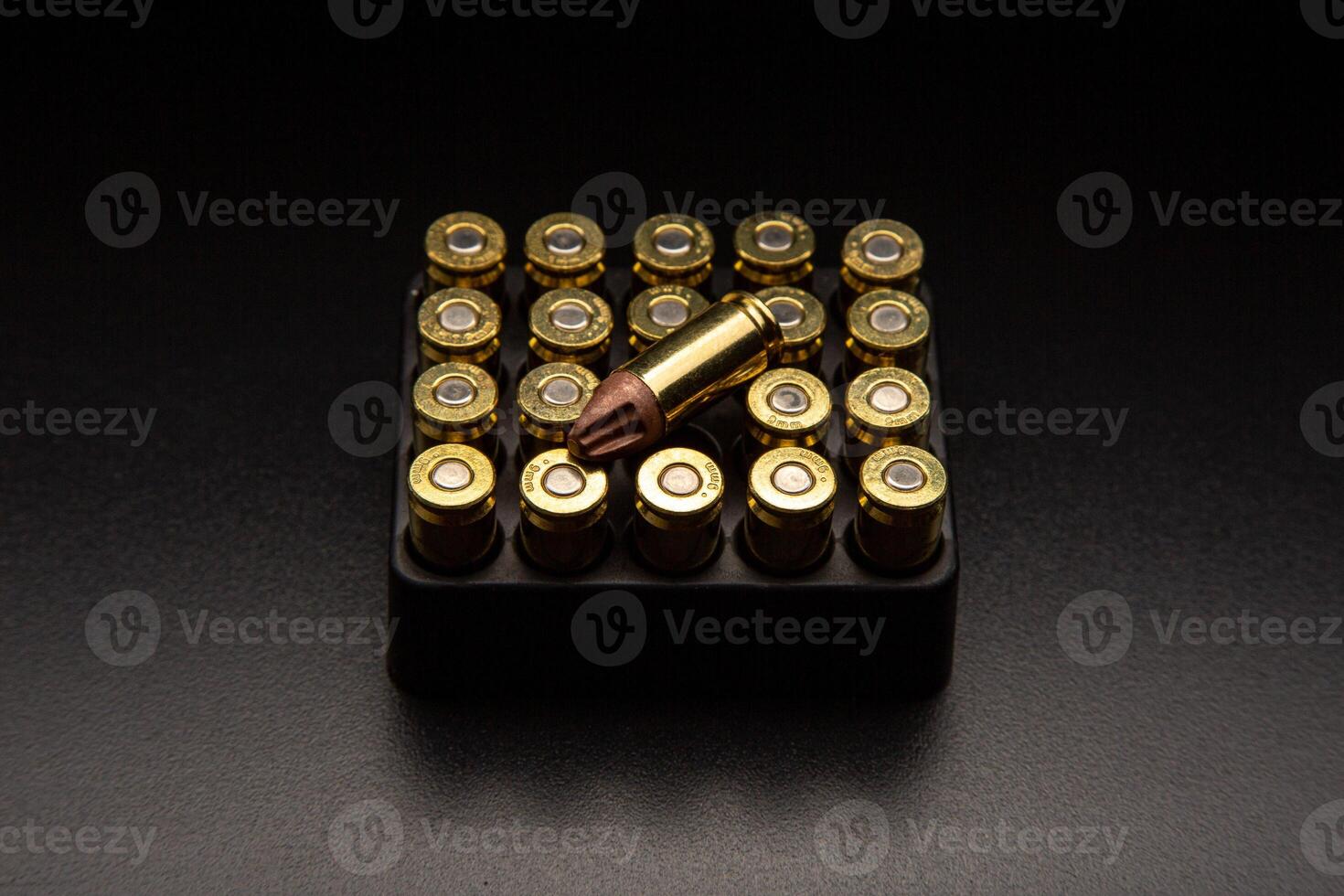 Pistol cartridges 9 mm on a smooth glossy surface with reflections. Ammunition for pistols and PCC carbines on a dark back. photo