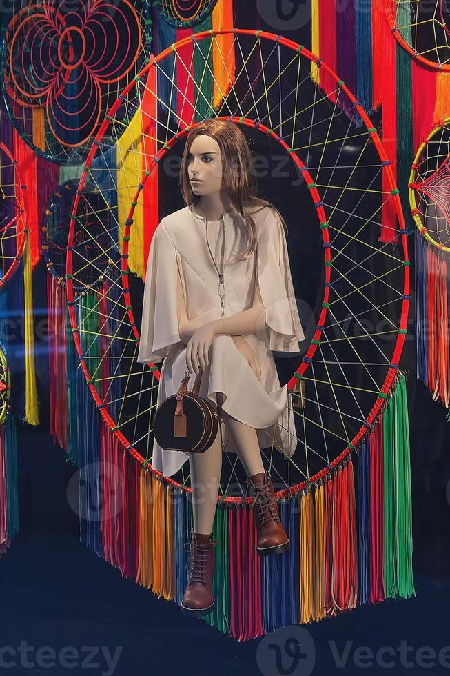 Female mannequin in an elegant dress and handbag in a fashion store window photo