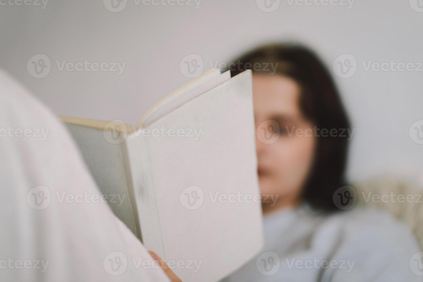 Young woman reading a book while sipping coffee at home photo