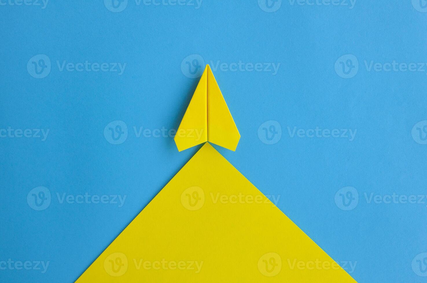 Top view of yellow paper airplane flying along the route on blue background with customizable space for text photo