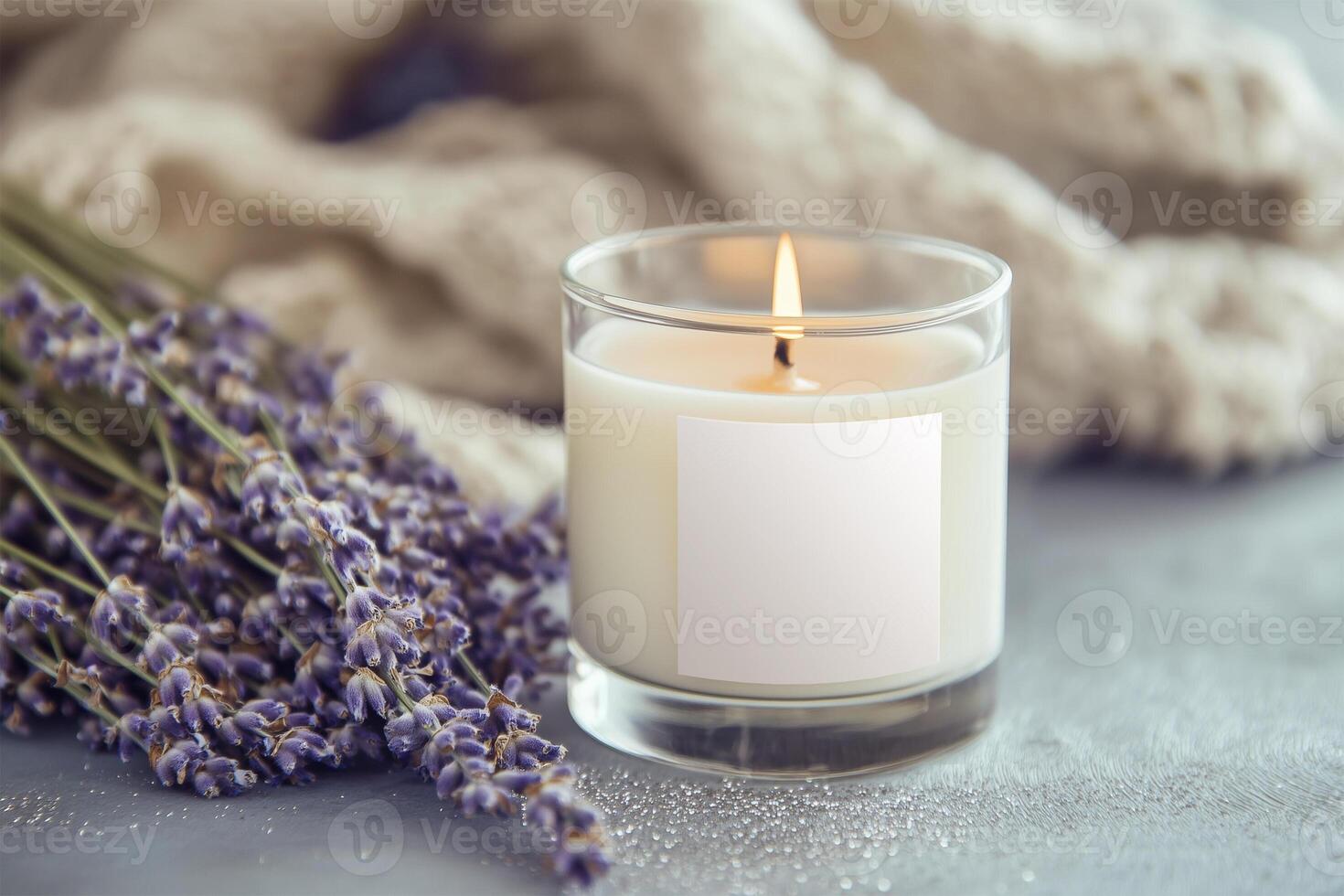 Candle in glass with a blank label, on table with fresh lavender. Styled photo product mockup