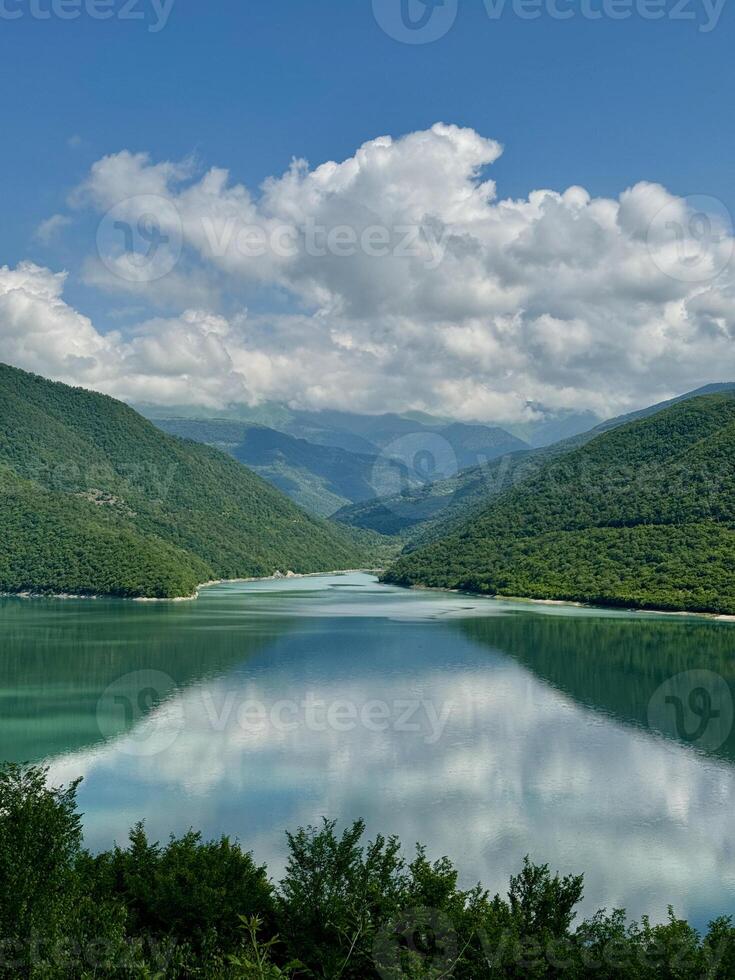 View of a lake between two lushy green hills with reflection in valley photo