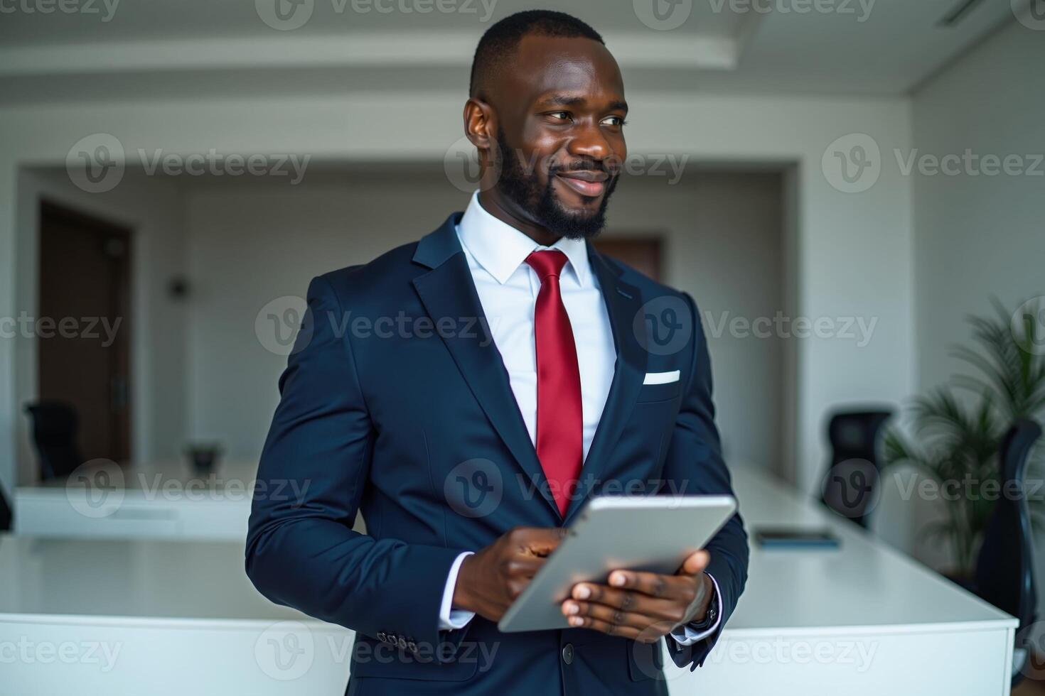 photo of man in navy suit outfit and red tie holding tablet in the office,