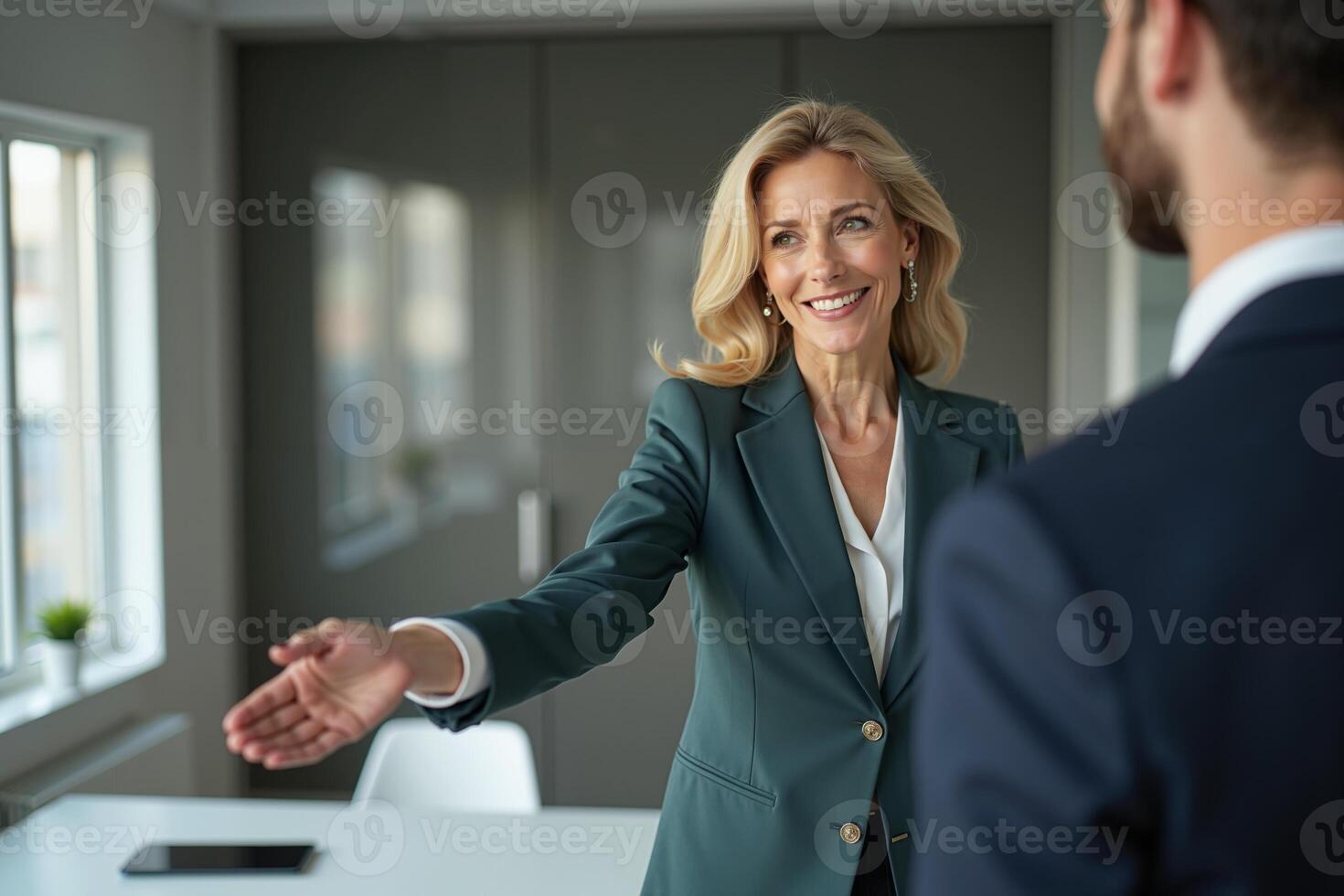 photo of woman in black blazer with open hand and colleagues in the office,
