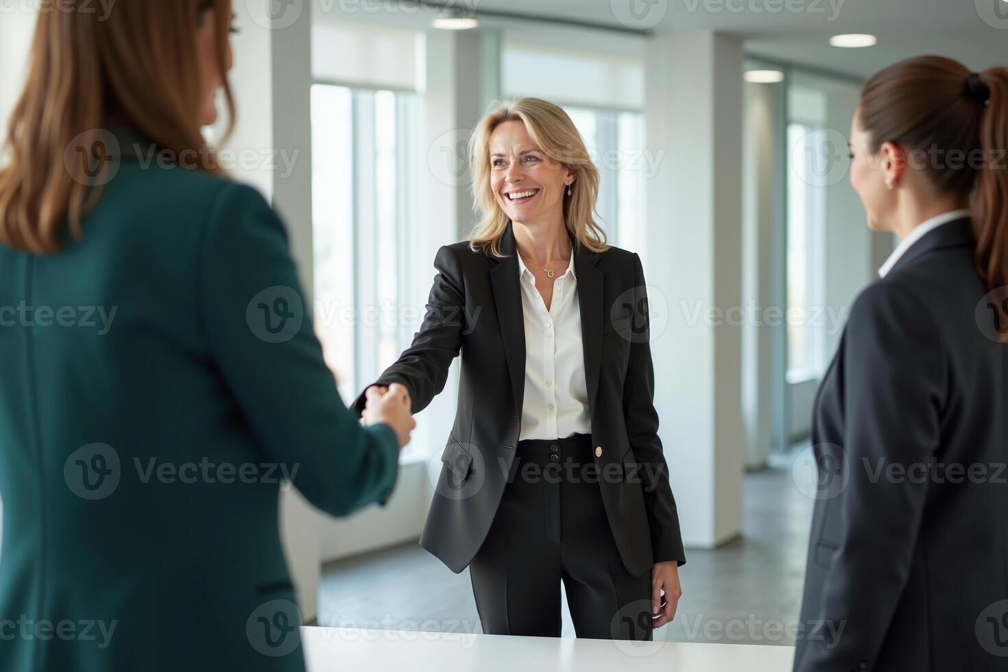 photo of woman in black blazer with open hand and colleagues in the office,
