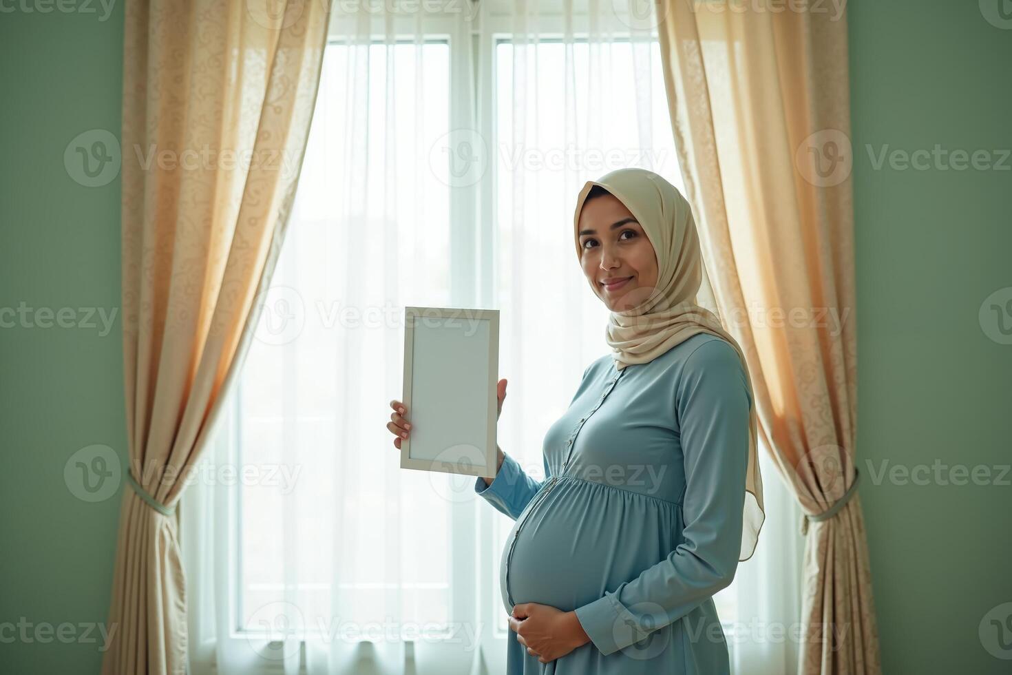 photo of muslim pregnant woman with hijab happy standing holding empty white photograph frame,