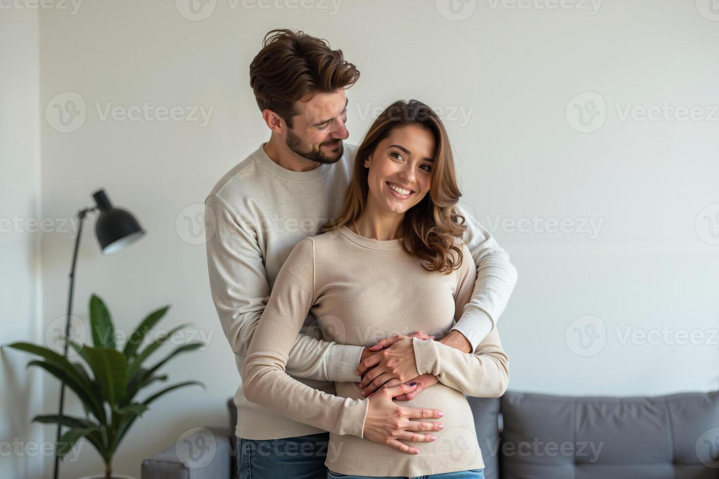 photo of couple man and pregnant woman relaxing standing both hands touching her belly at house,