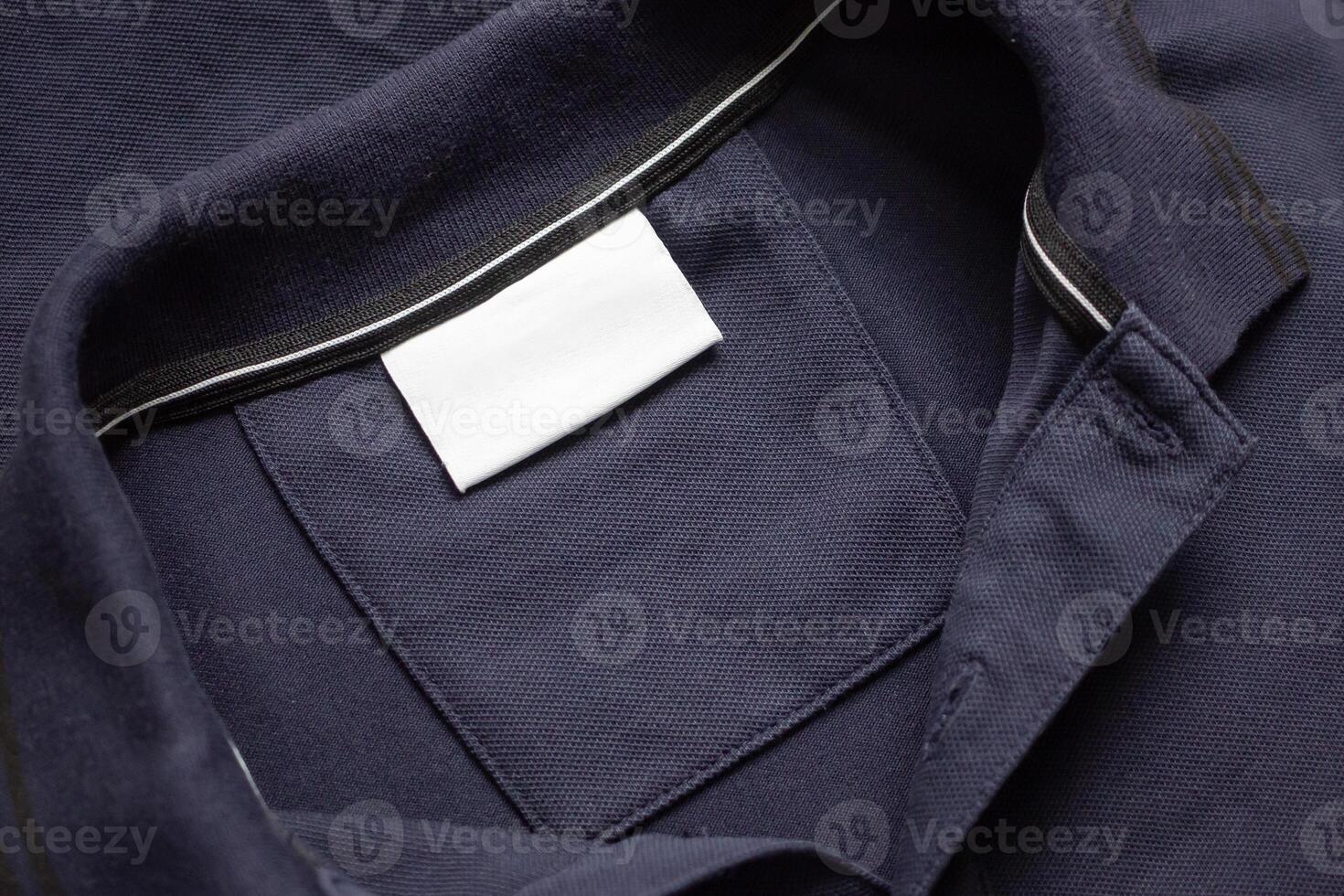 Blank white laundry care clothes label on black shirt fabric texture background photo