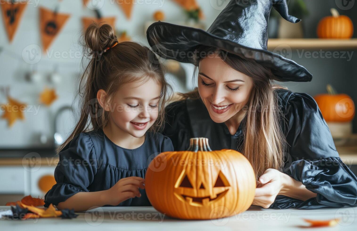 A mother and daughter sit at a table decorating a pumpkin for Halloween in festive costumes photo