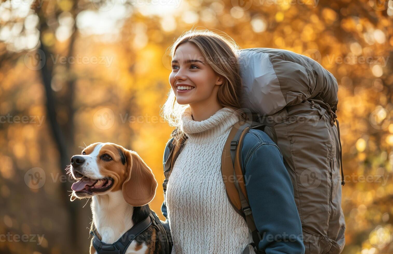 A joyful woman strolls in an autumn park with her beagle and a sleeping bag photo