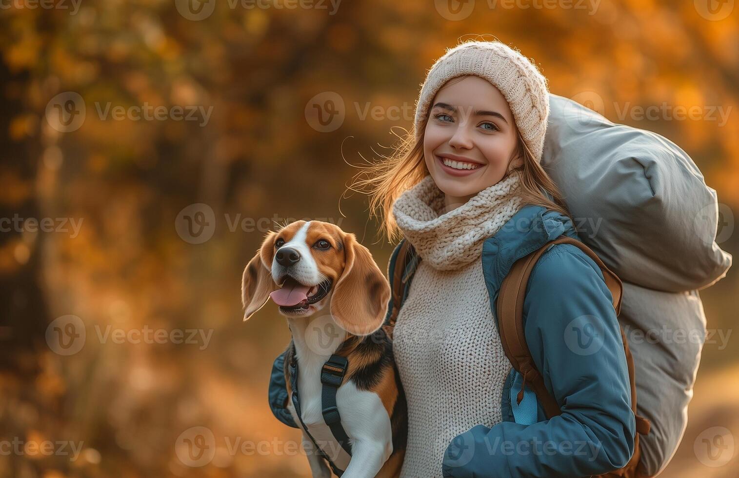 A joyful woman strolls in an autumn park with her beagle and a sleeping bag photo