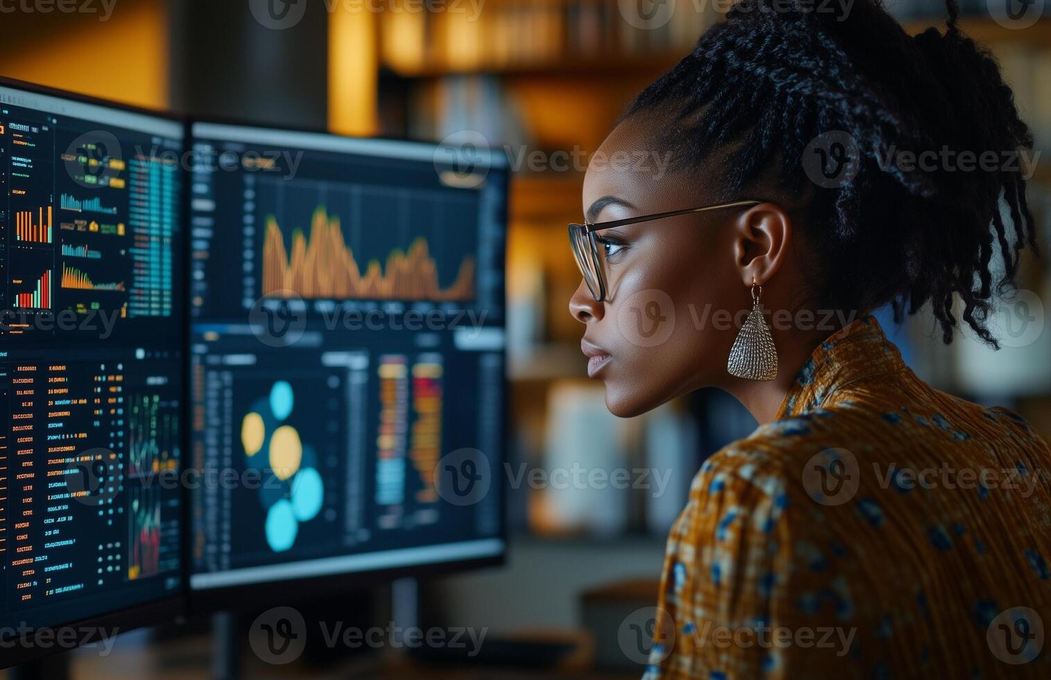 A Black woman analyzing business data on two monitors in a modern office photo