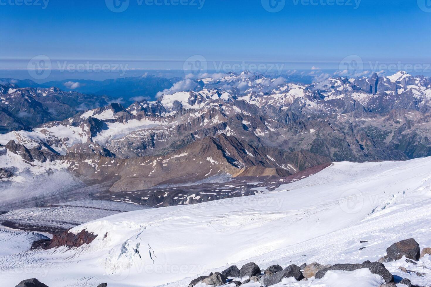 top view of the high mountains above the clouds from the glacier on the slope of Mount Elbrus photo