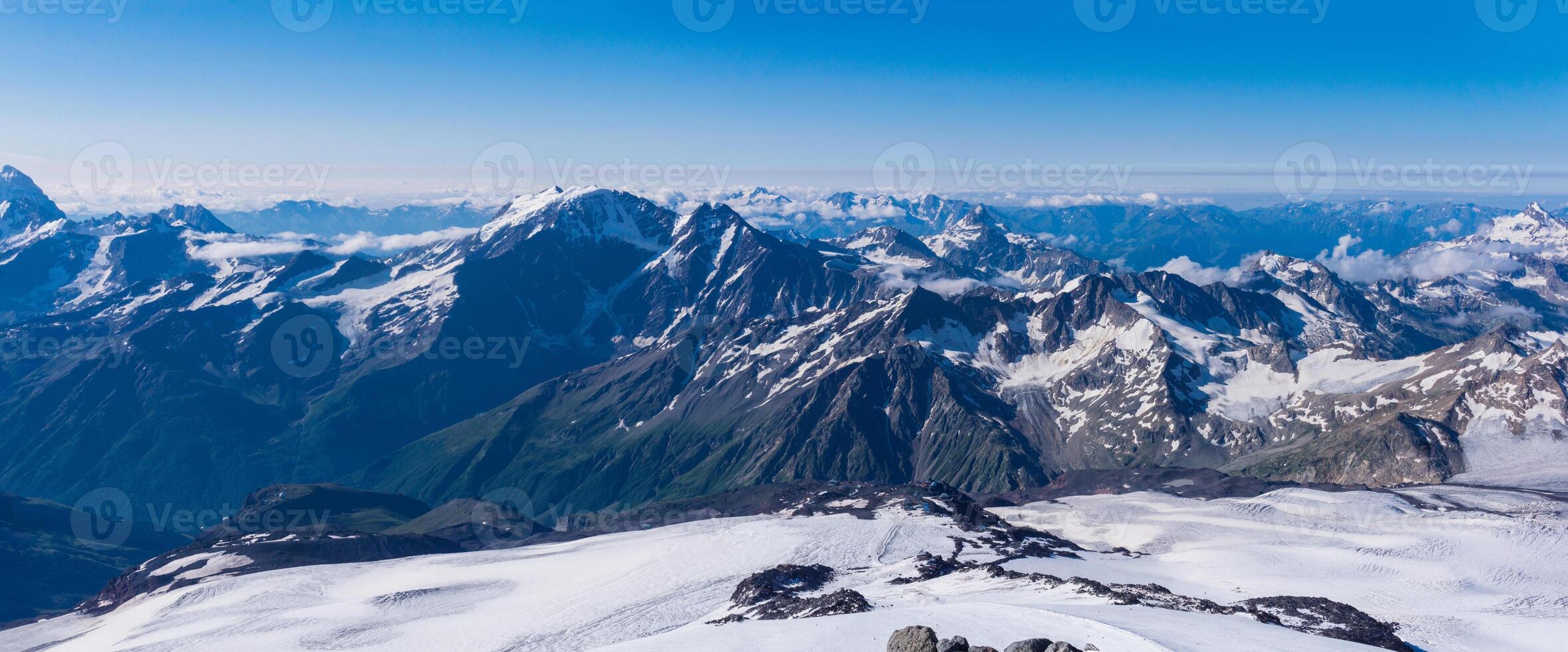 panoramic view of the high mountains above the clouds from the snowy slope of Mount Elbrus photo