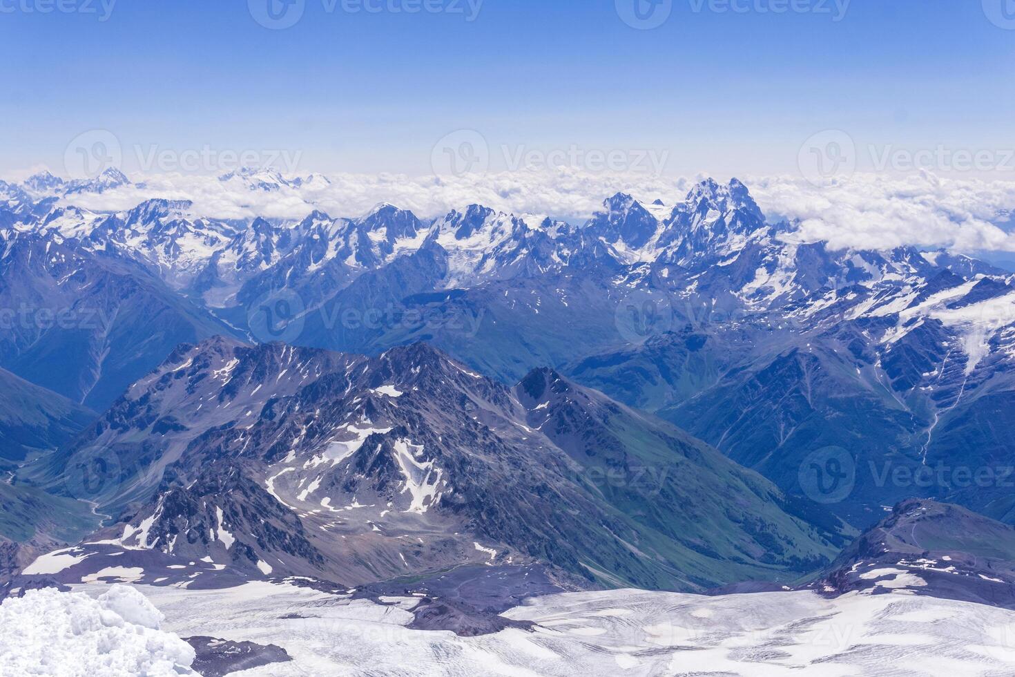 landscape of the high mountains above the clouds from the snowfield on the slope of Mount Elbrus photo