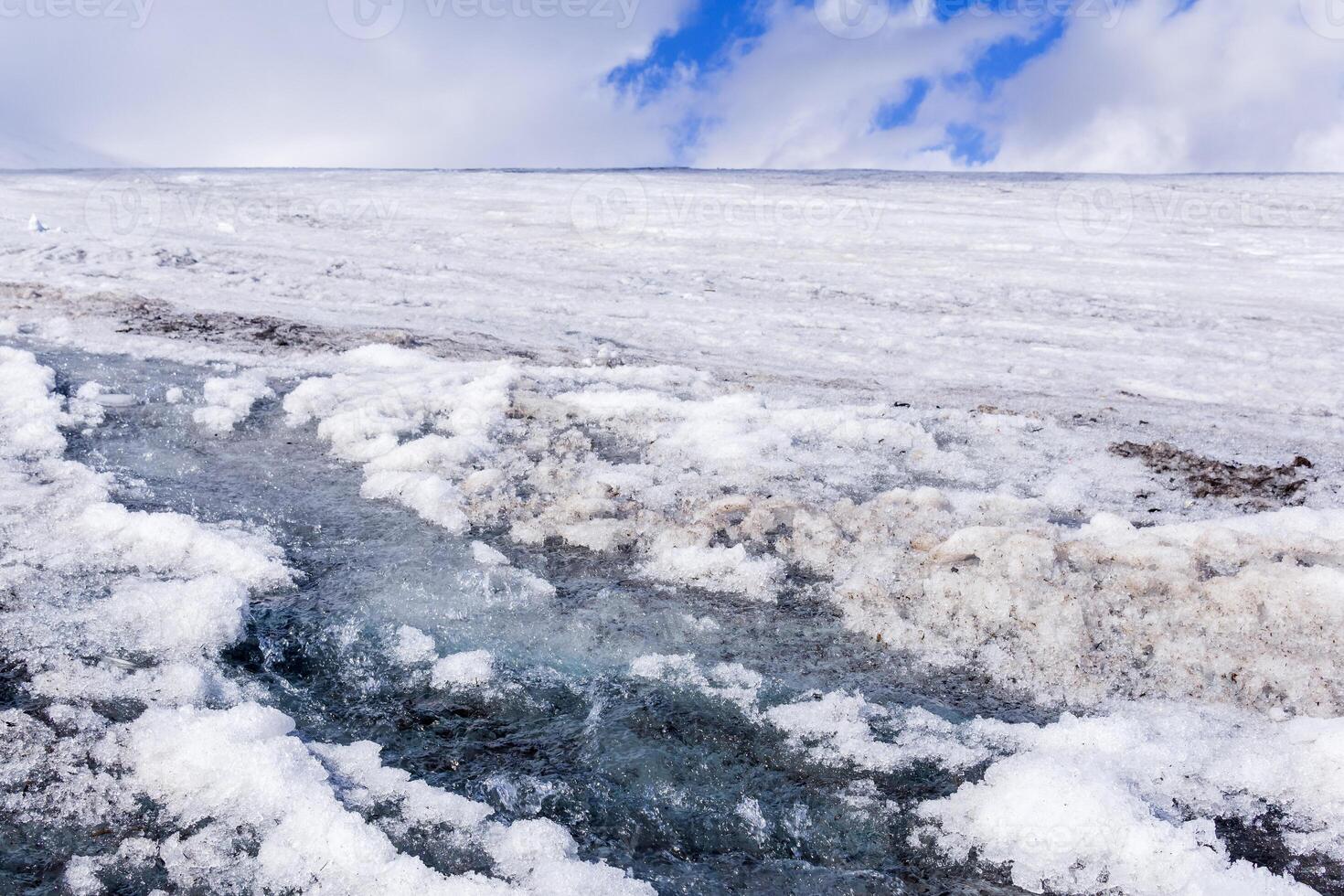 streams of water on the surface of a melting high-mountain glacier photo