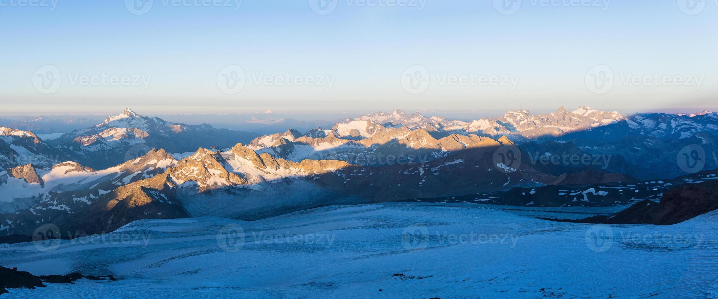 dawn panoramic view of the high mountains above the clouds from the glacier on the slope of Mount Elbrus photo