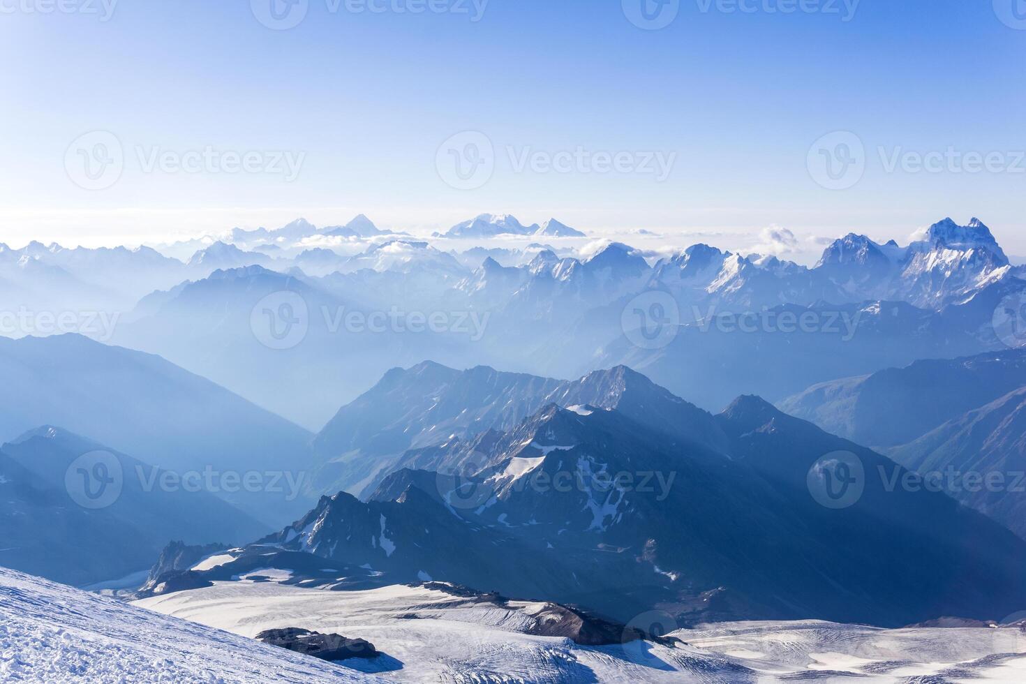 view from highland snowy slope to misty mountains in the rays of dawn photo