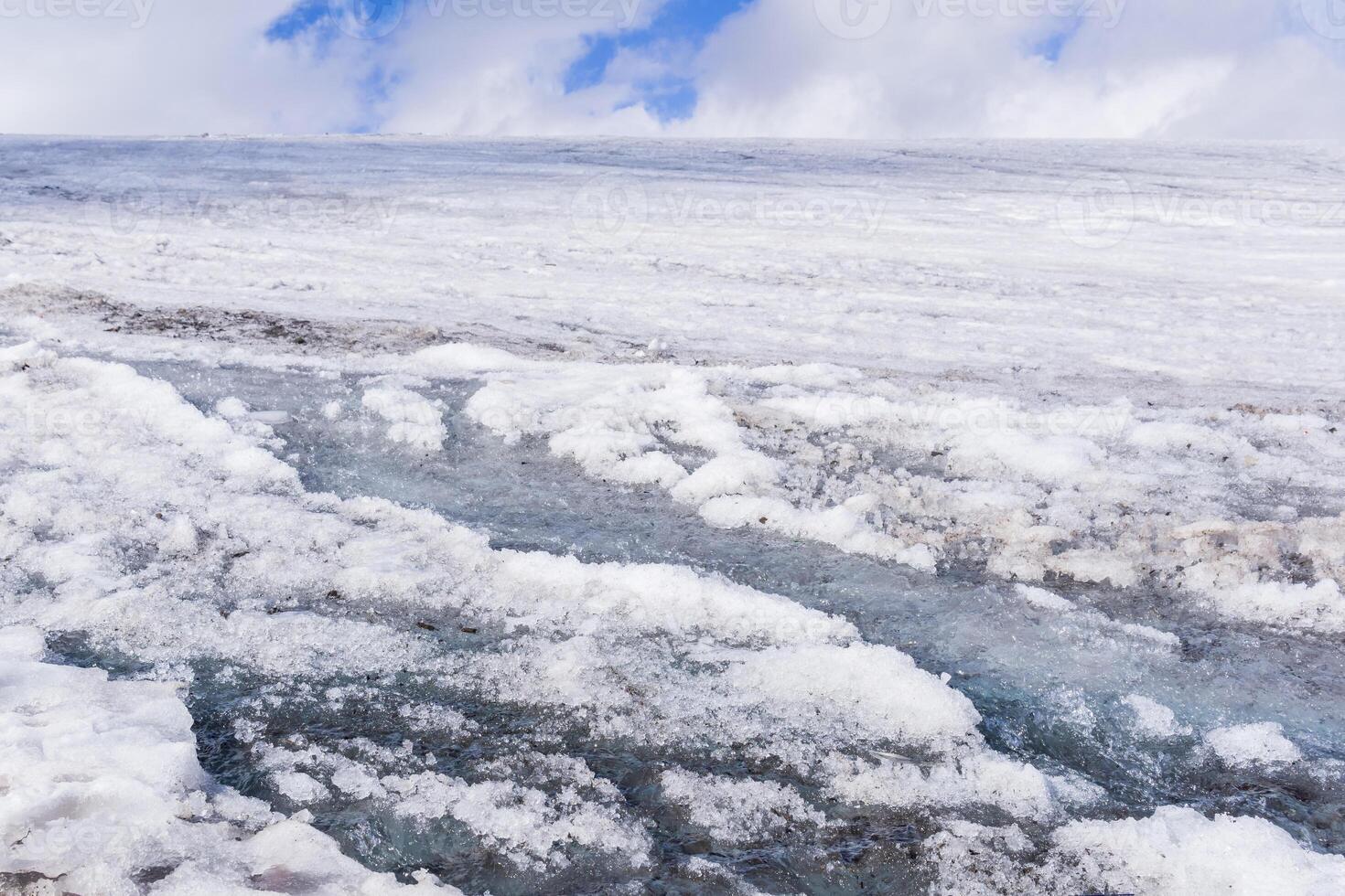 streams of water on the surface of a melting high-mountain glacier photo
