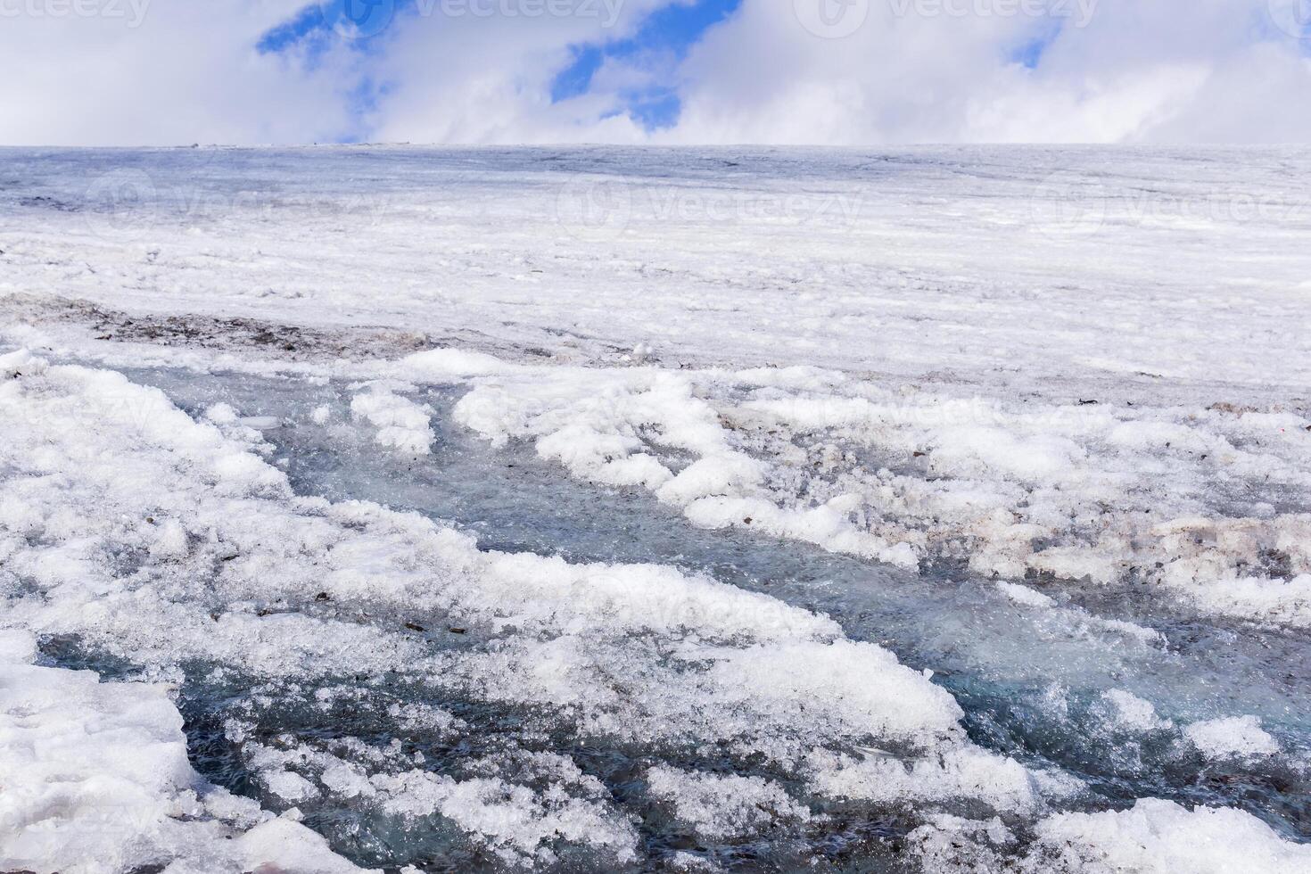 streams of water on the surface of a melting high-mountain glacier photo