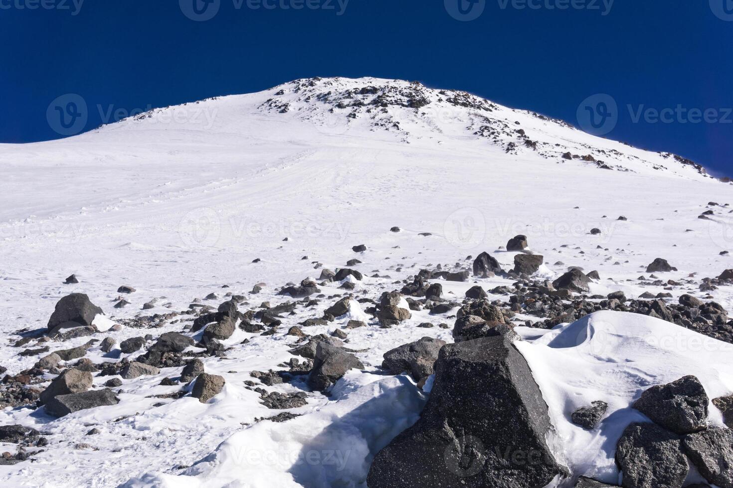 snowy mountain landscape with dark highland sky, view of the eastern peak of Mount Elbrus from a snowfield near Pastukhov Rocks photo