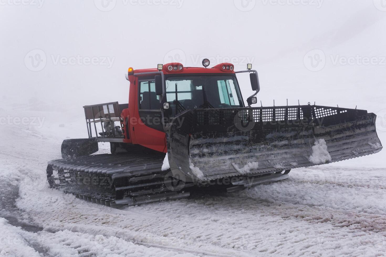 snowcat on a melting ski slope in thick cloudy fog photo
