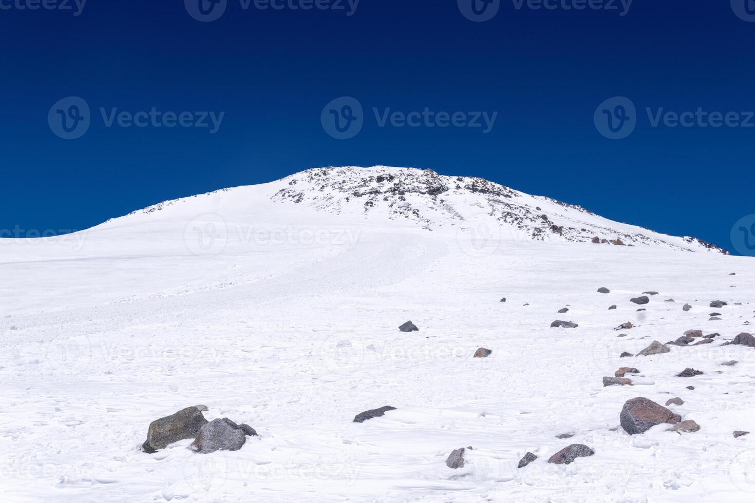 snowy mountain landscape with dark highland sky, view of the eastern peak of Mount Elbrus from a snowfield near Pastukhov Rocks photo
