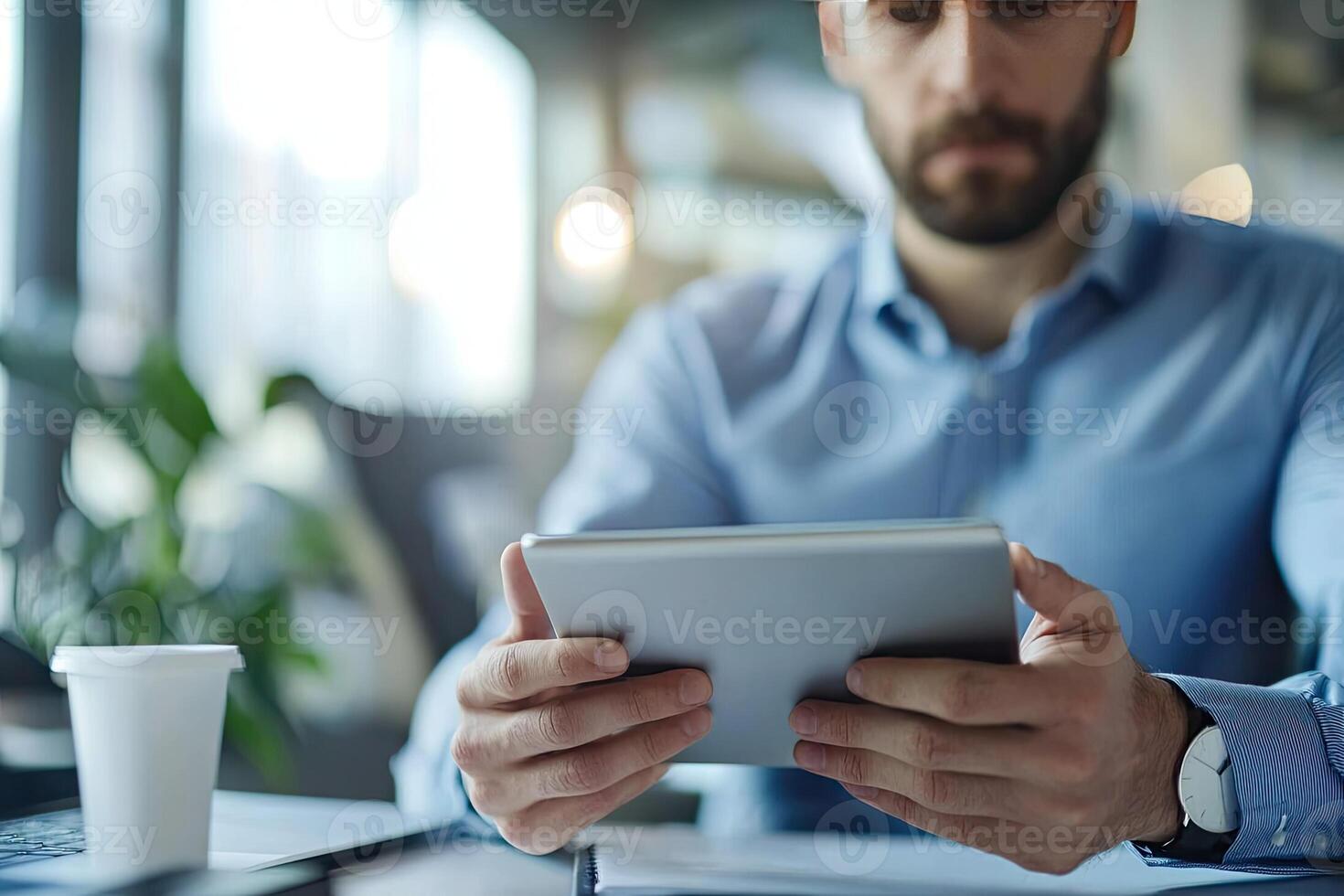 Close up of young businessman using digital tablet while sitting at his working place in office. Businessman using digital tablet photo