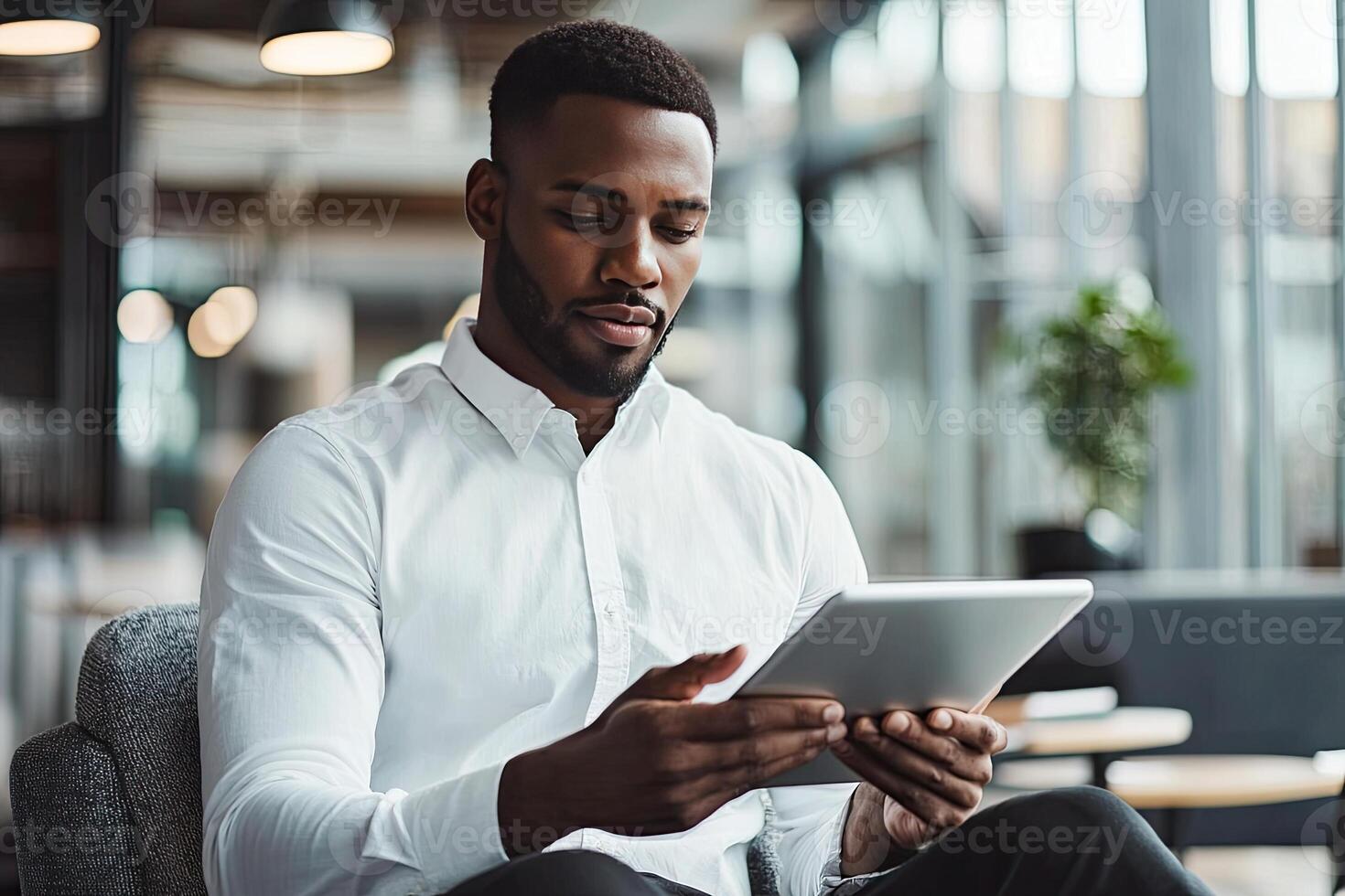 Close up of young businessman using digital tablet while sitting at his working place in office. Businessman using digital tablet photo