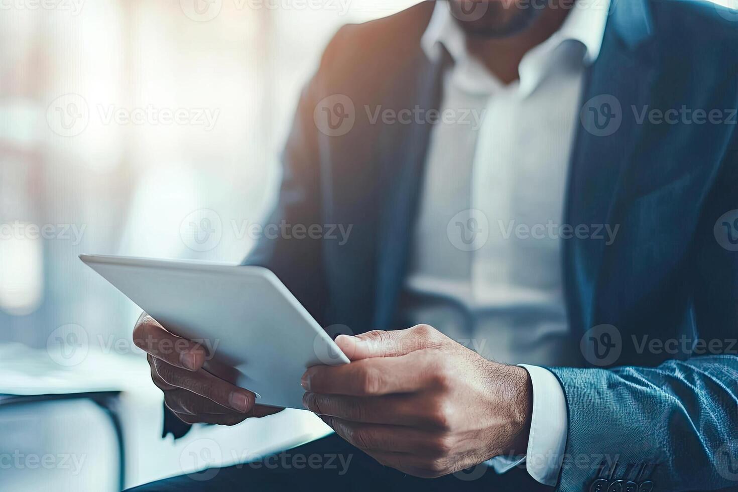 Close up of young businessman using digital tablet while sitting at his working place in office. Businessman using digital tablet photo