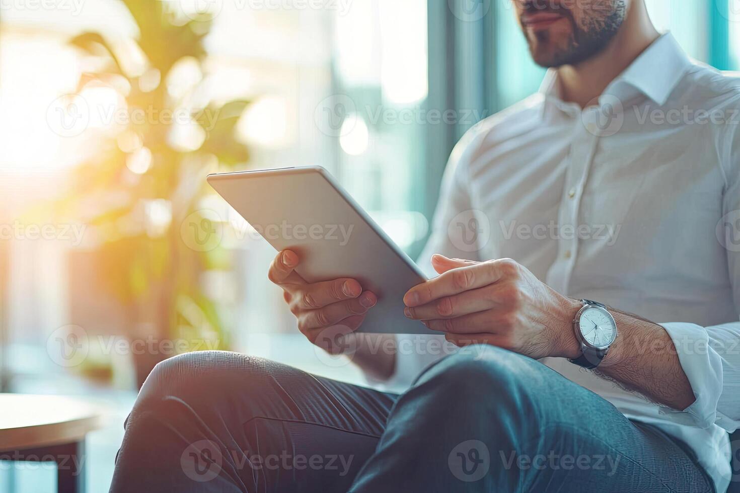 Close up of young businessman using digital tablet while sitting at his working place in office. Businessman using digital tablet photo