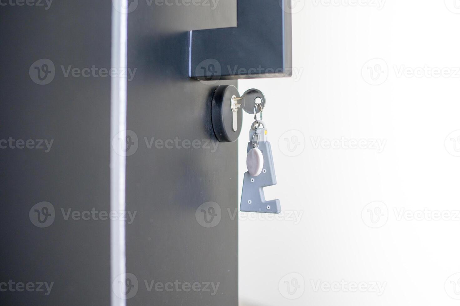 A house key with a key ring inserted at the door lock. Buy new home or concept photo