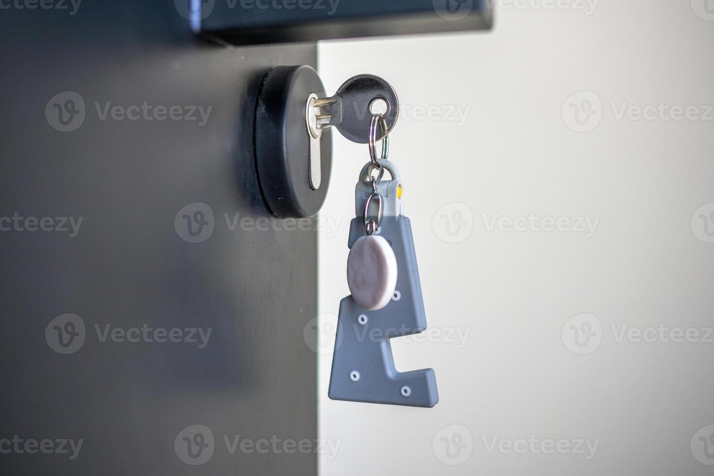 A house key with a key ring inserted at the door lock. Buy new home or concept photo