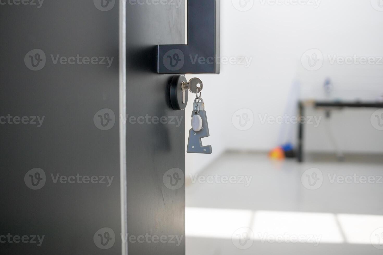 A house key with a key ring inserted at the door lock. Buy new home or concept photo