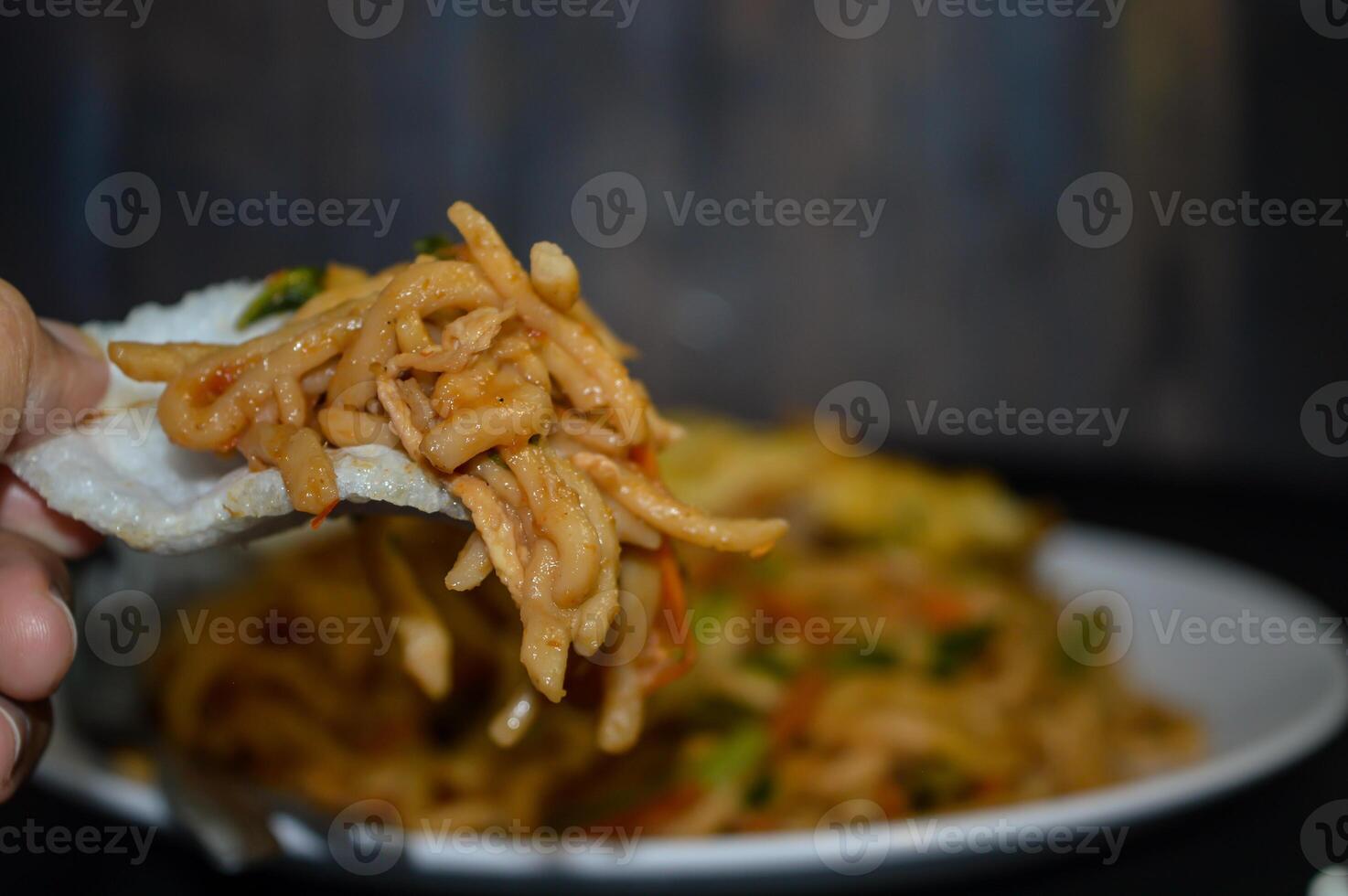 Fried noodles are one of the most popular foods in Southeast Asia, including Indonesia. Served with eggs and vegetables, on a plate photo