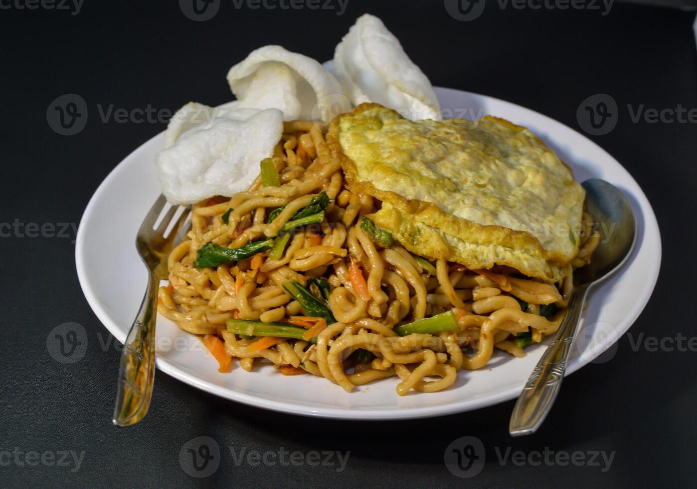 Fried noodles are one of the most popular foods in Southeast Asia, including Indonesia. Served with eggs and vegetables, on a plate photo