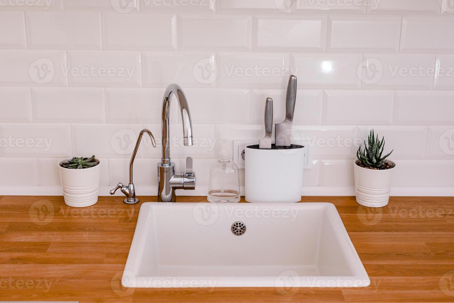 Clean white sink on wooden table in white kitchen photo