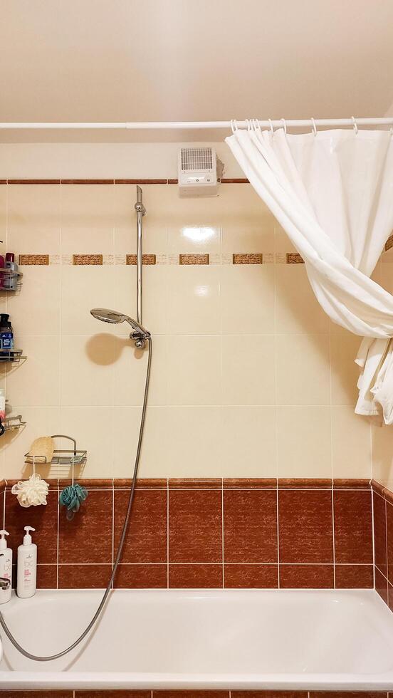 Prague, Czech republic - October 6, 2023. A cozy bathroom with a shower and bathtub surrounded by tiles and Vents turbo fan photo