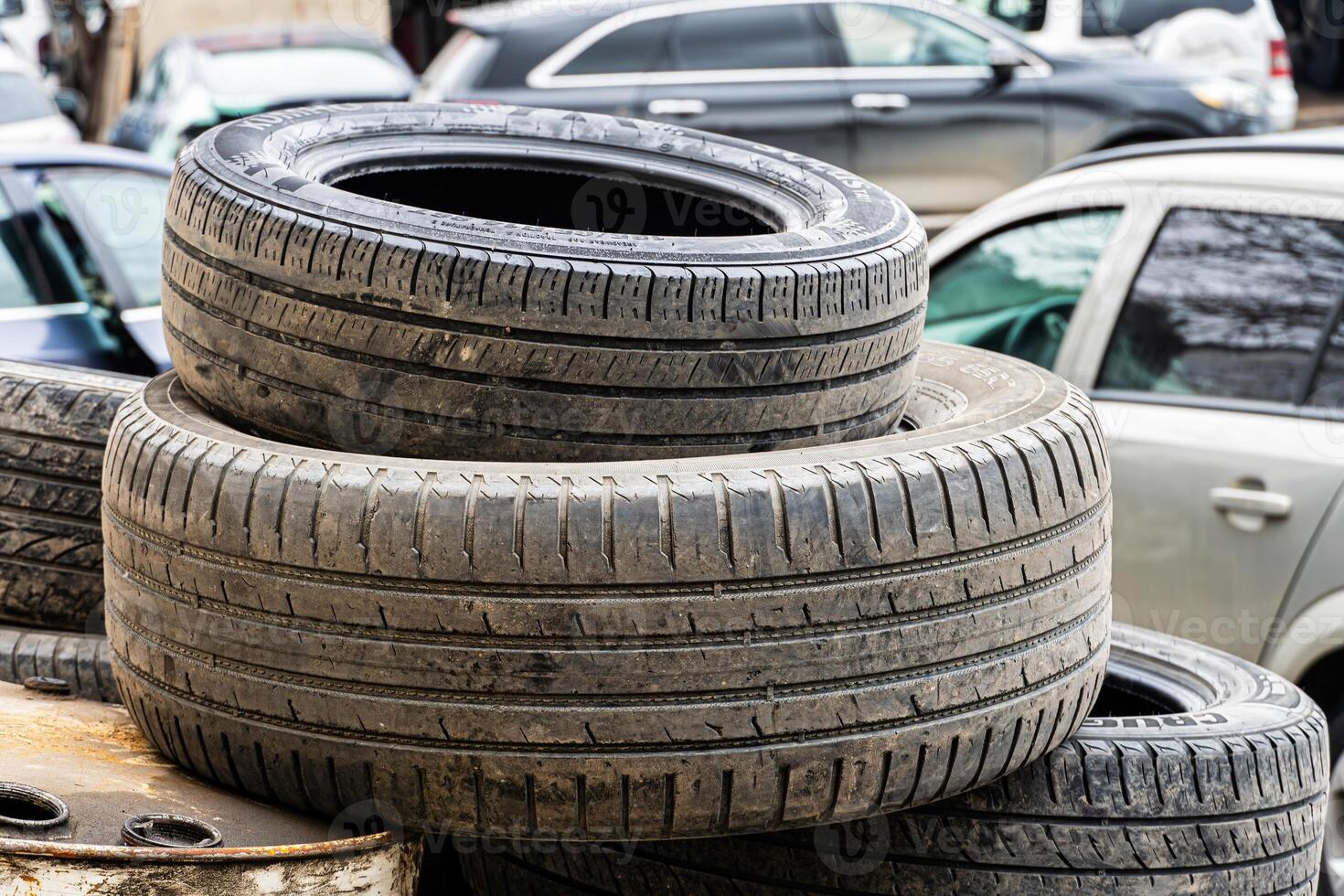 Stacked Used Tires Near Cars photo